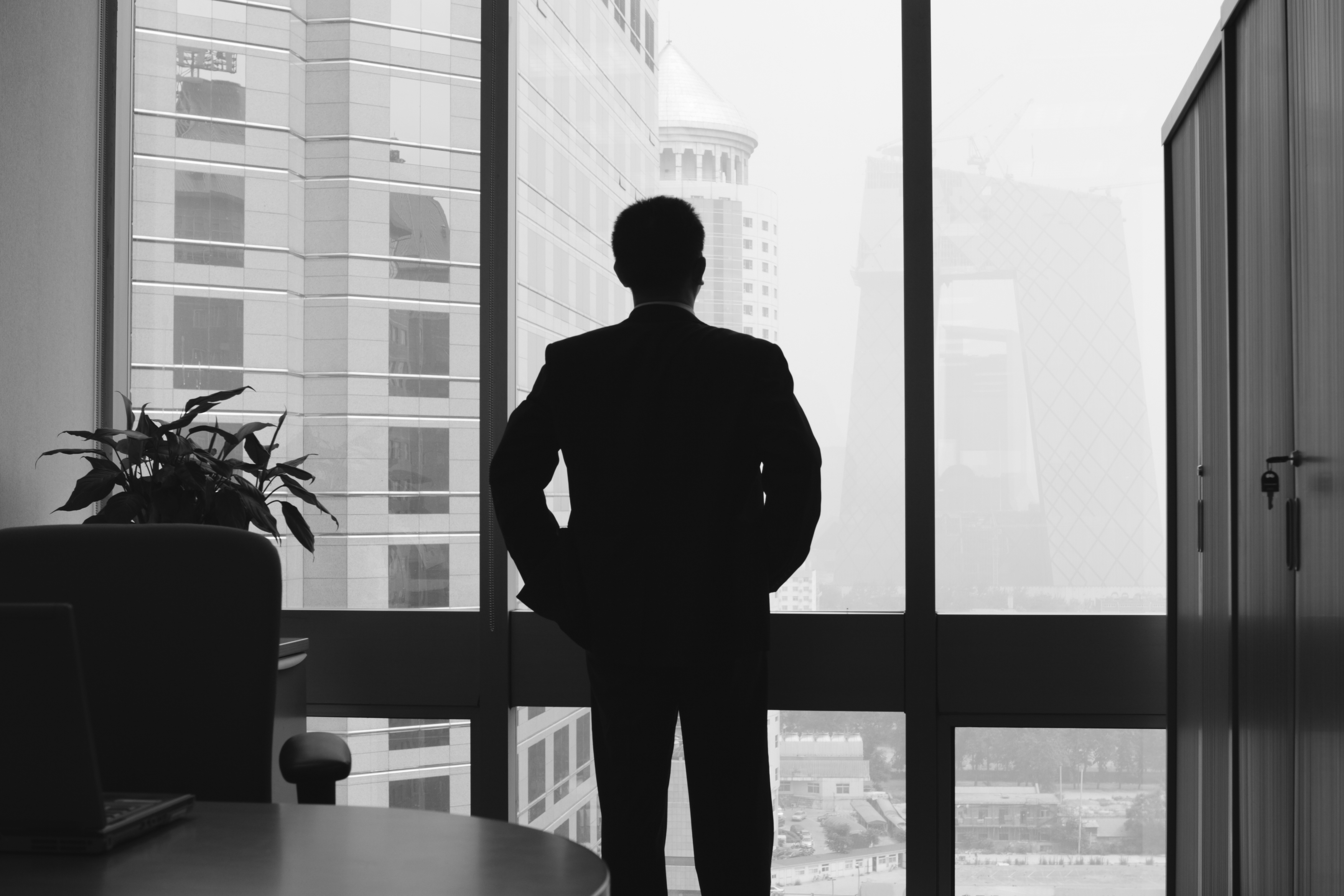 Eine Person blickt aus einem Bürofenster auf moderne Architektur